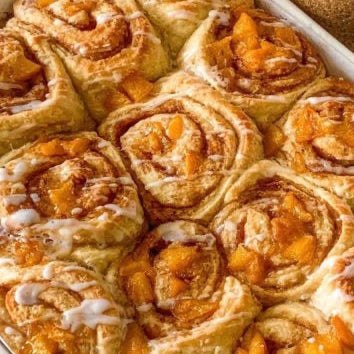 Box of 4 peach cinnamon buns with swirled brioche and cream glaze, featuring orange cardamom flavors