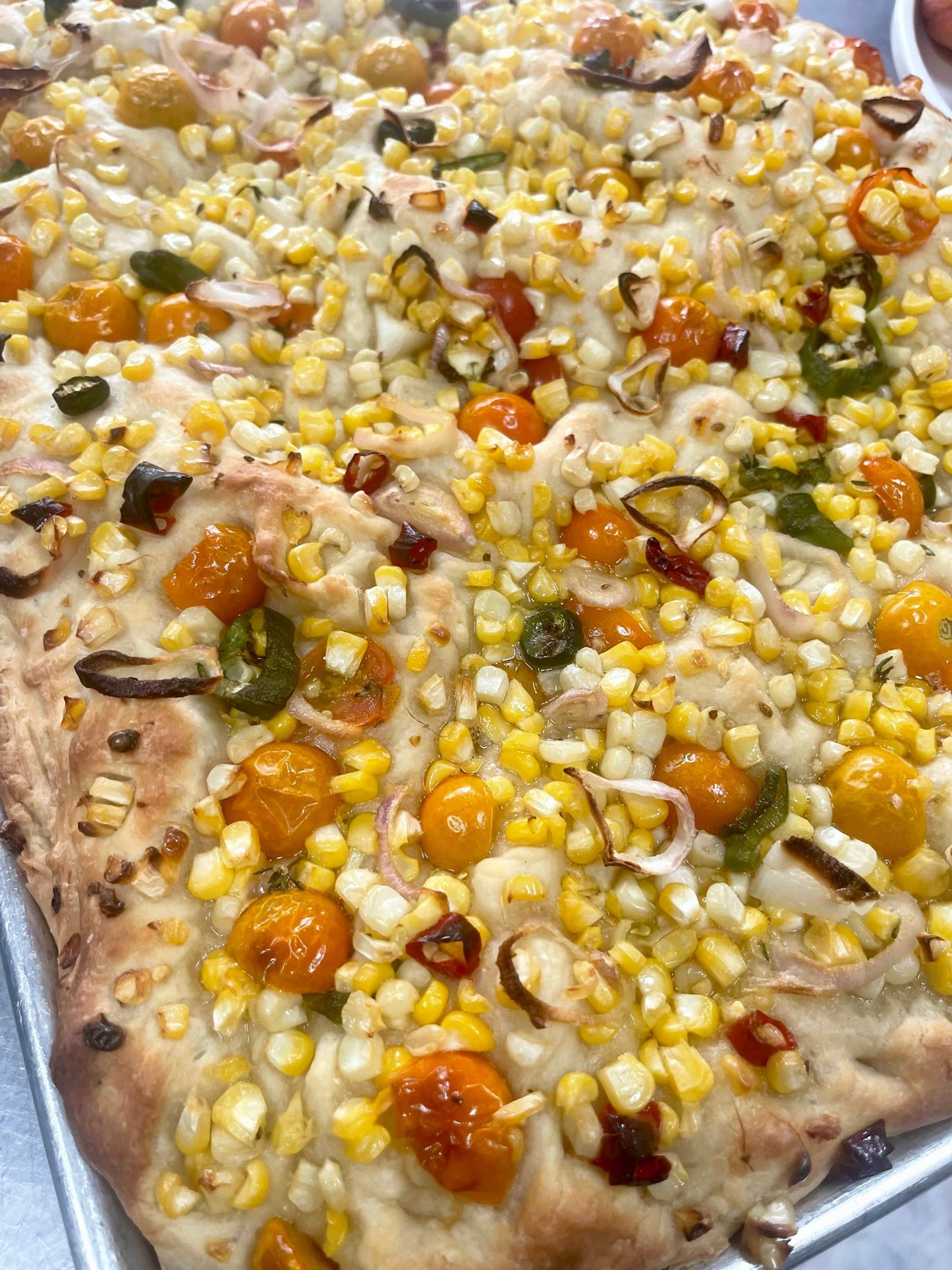 Corn Poblano Golden Tomato Focaccia topped with fresh corn, golden tomatoes, and poblano peppers