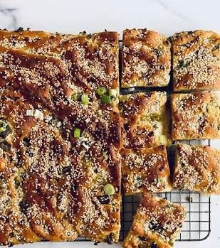 Sesame Scallion Focaccia bread with spring onions, sesame seeds, and flaky salt on a wooden board