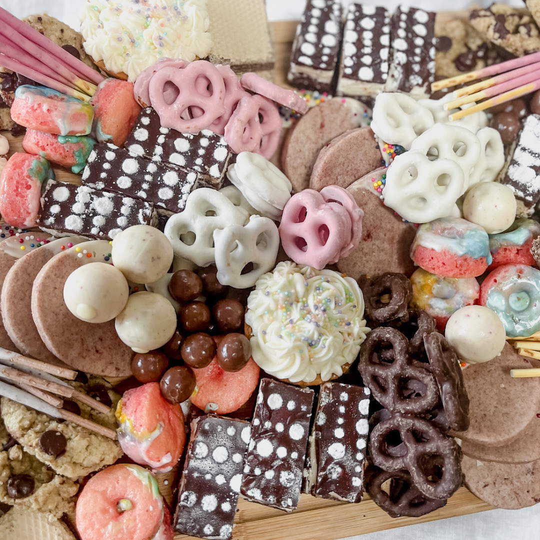 Neapolitan Vanilla Chocolate Strawberry dessert board with cupcakes, brownies, cookies, and mini donuts