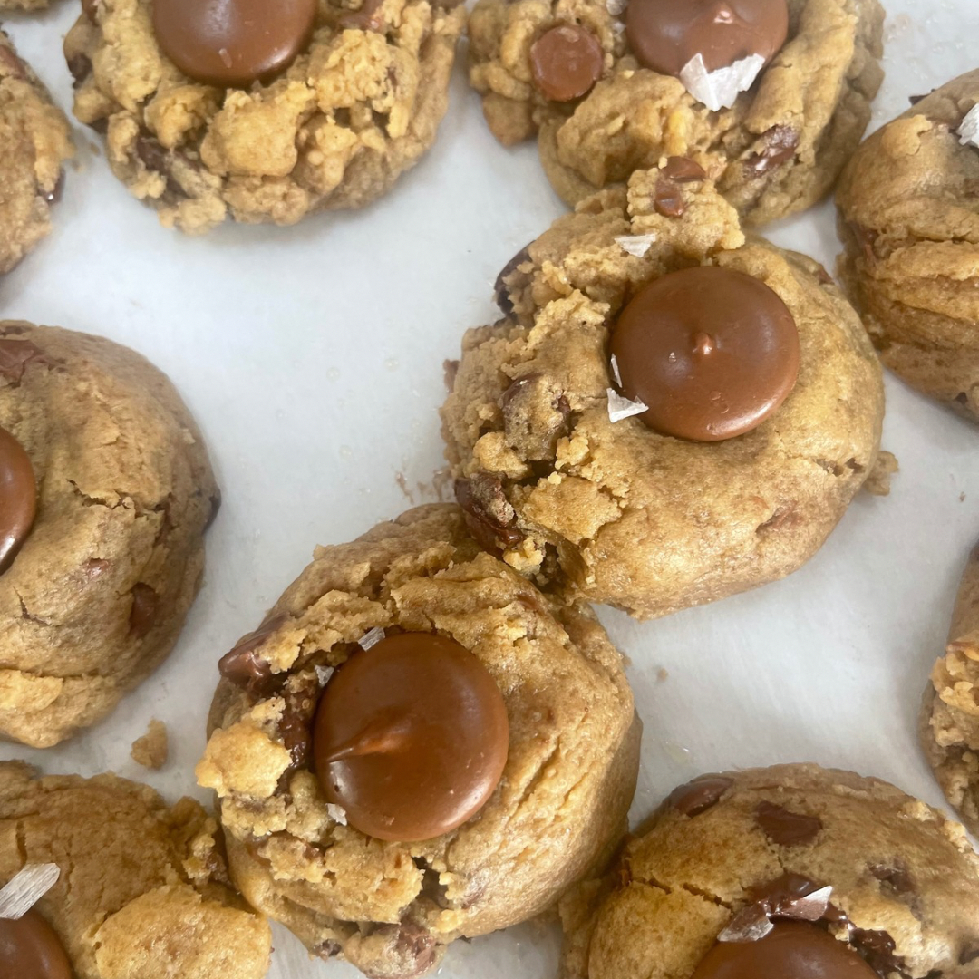 Brown butter chocolate chip cookies with dark and milk chocolate chunks and flaky salt in a box of four
