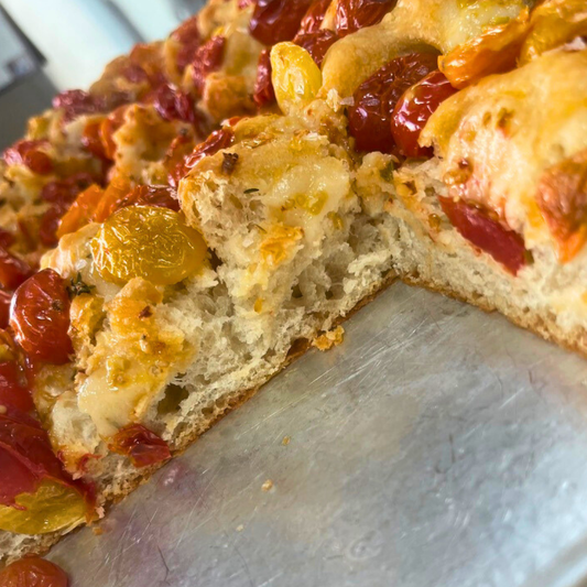 Tomato Thyme Focaccia topped with cherry tomatoes, garlic, Calabrian chile flakes, and fresh thyme slices