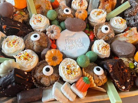 Halloween Dessert Board with spooky themed cookies, cupcakes, brownies, pumpkin decorations, and "Happy Halloween" cake centerpiece