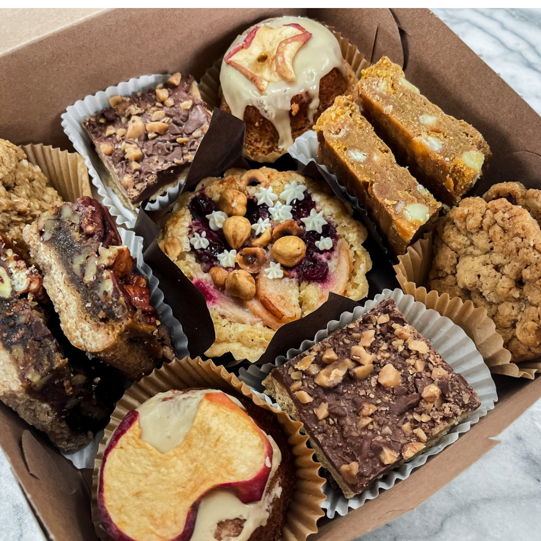 Thanksgiving Treat Feast dessert box with pumpkin blondie, oatmeal cookie sandwich, pear cranberry tartlet, pecan bar, toffee bars, and apple cake