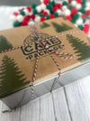 Festive holiday cookie tin box tied with red, white, and green twine and decorated with green pine tree prints