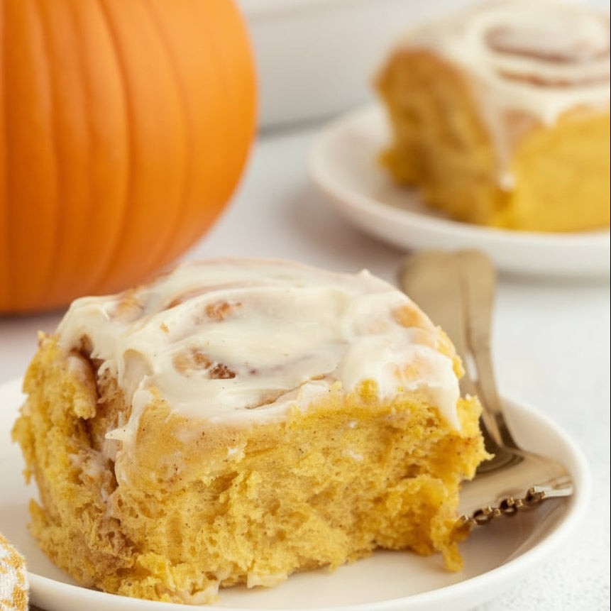 Pumpkin cinnamon buns with creamy icing and pumpkin puree on brioche dough