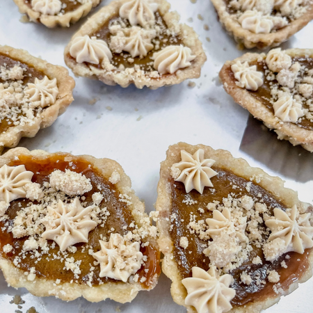 Thanksgiving Pumpkin Biscoff Tartlets with spiced pumpkin filling, Biscoff shortbread crust, cookie butter caramel, cream, and cookie crumble topping