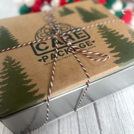 Festive holiday cookie tin wrapped with red, white, and green twine featuring seasonal cookie sandwich flavors.