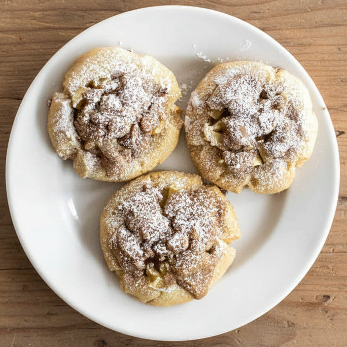 Three apple crumb cookies dusted with powdered sugar.